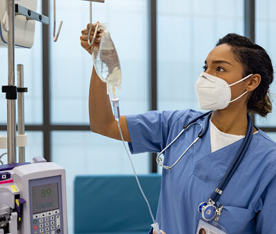 African American nurse at the hospital putting an IV Drip on a patient - healthcare and medicine concepts